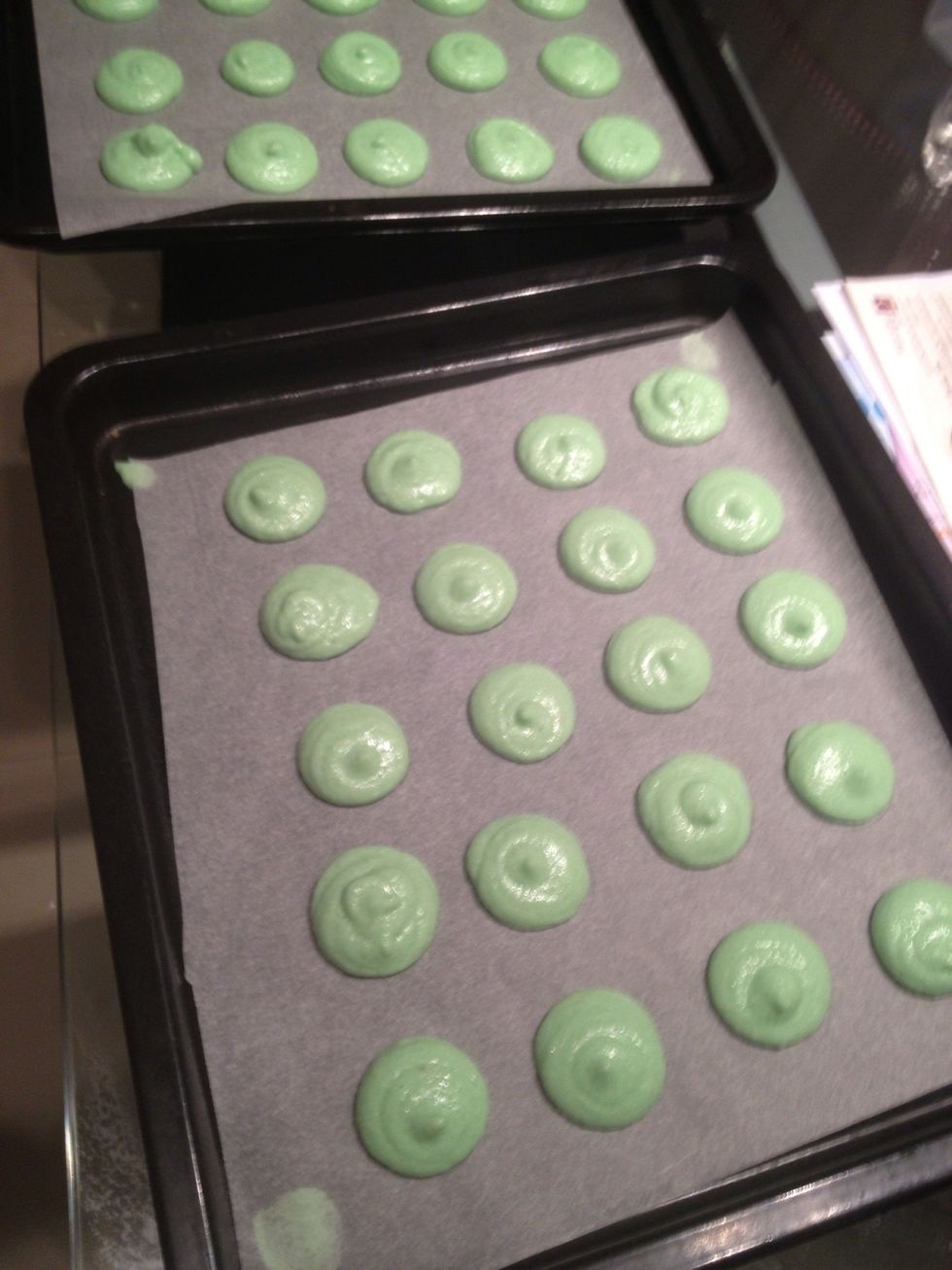 After piping, give the trays a few taps to make the bubbles inside the macarons pop.