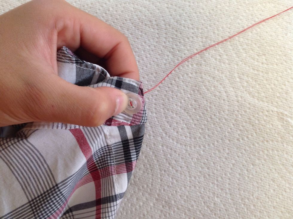 After pulling thread completely through, poke needle back down the empty hole directly across, making sure that thread is tight.