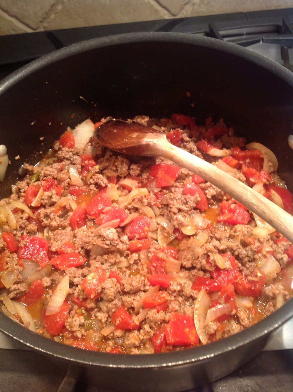 After the beef is brown, add the can of tomatoes and seasonings. Cooke for another 5 minutes.