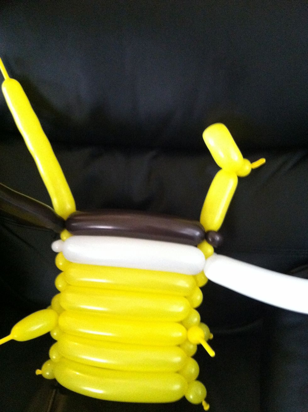 After the brown balloon has been secured on both sides, take one of the yellow legs and put a little bubble at the top of the balloon. Use this bubble to create a loop for the foot.