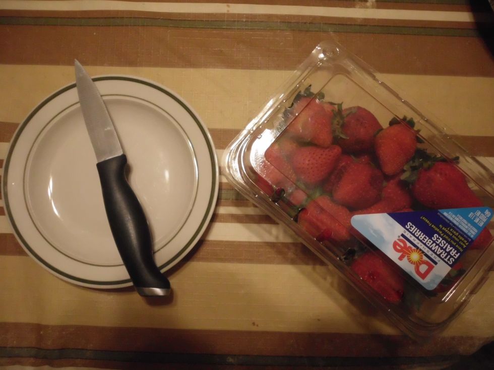 after the cheese cake is cover with sour cream, the next is to take out the strawberries, and cut the stems off, and then cut them or dice them. "Remember you don't have to have whole strawberries".