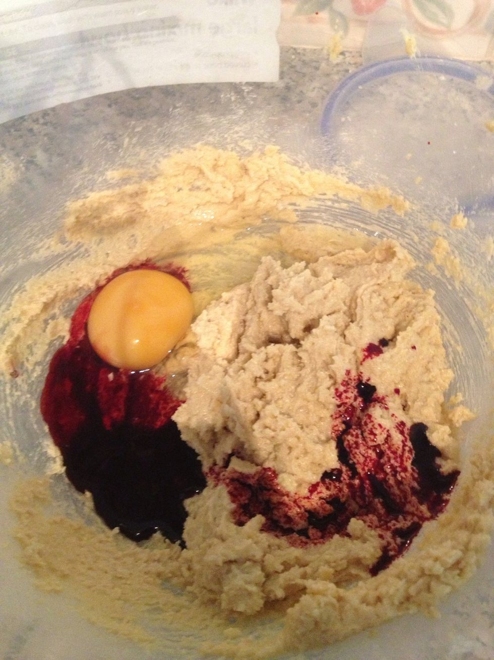 After the sugars are successfully mixed with butter, pour the food colouring and crack an egg into mix and of course whisk\u2026until there's a liquid consistency.