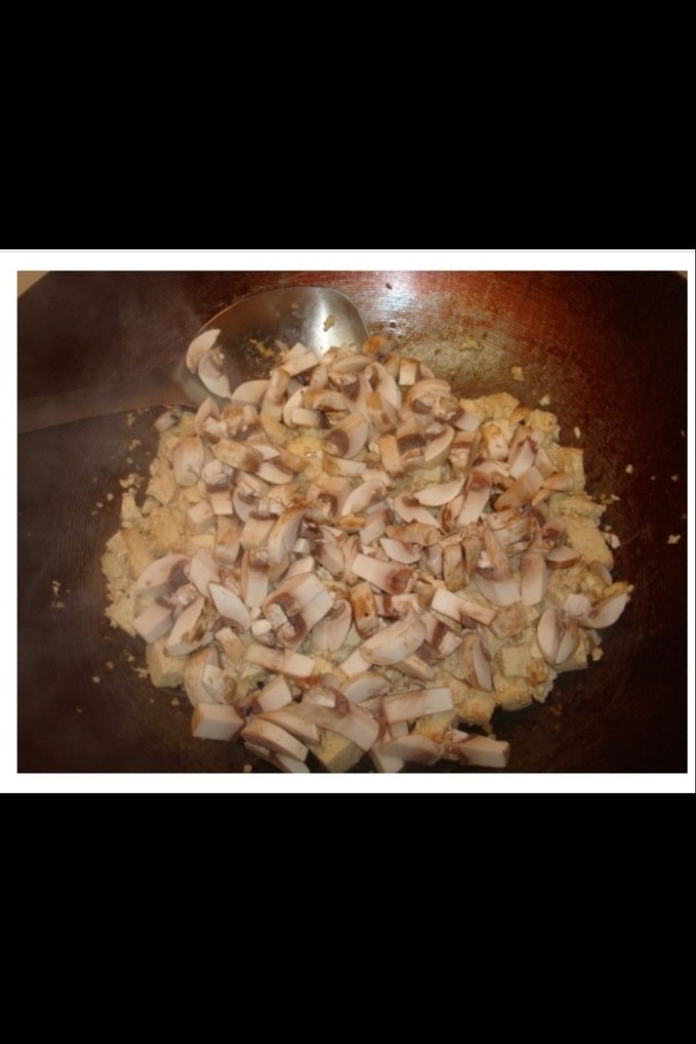 After the tofu has cooked for a few minutes, add the mushrooms and continue to stir fry.