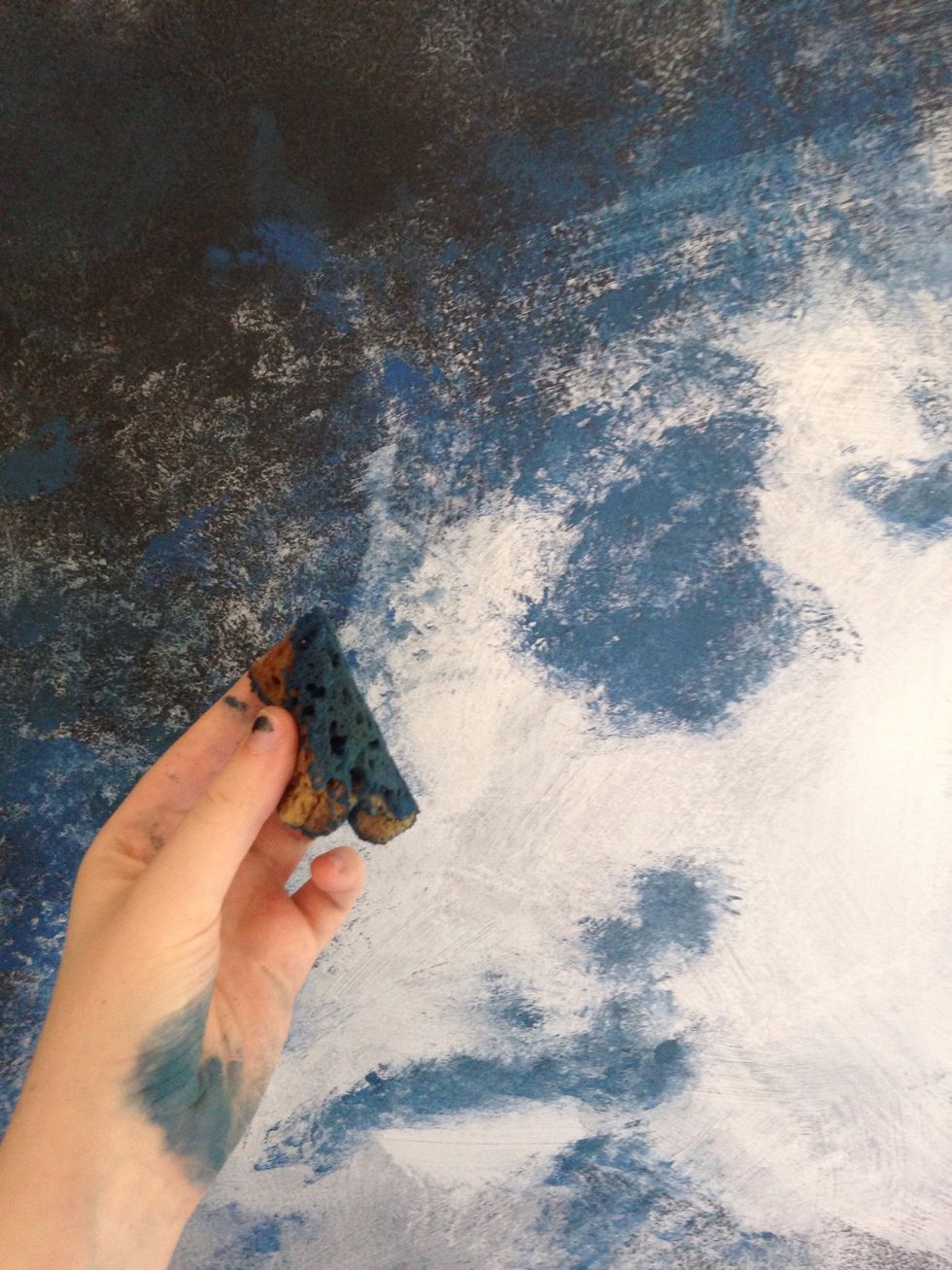 After the white is on, mix a little black with blue and purple. Sponge this on by patting lightly-