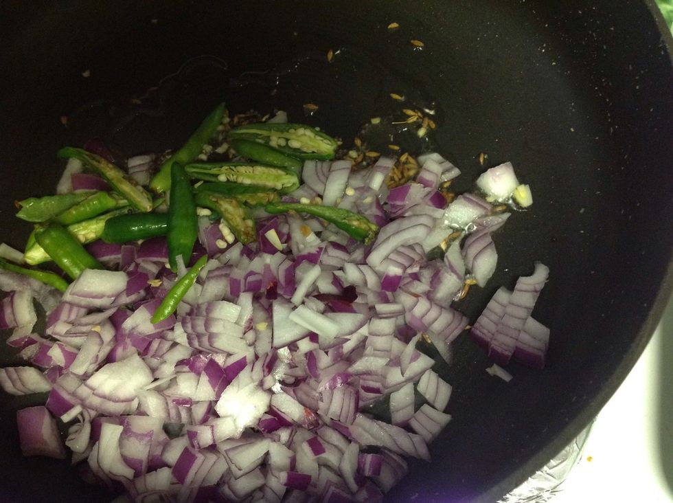 After they start spluttering add onions and green chillies.