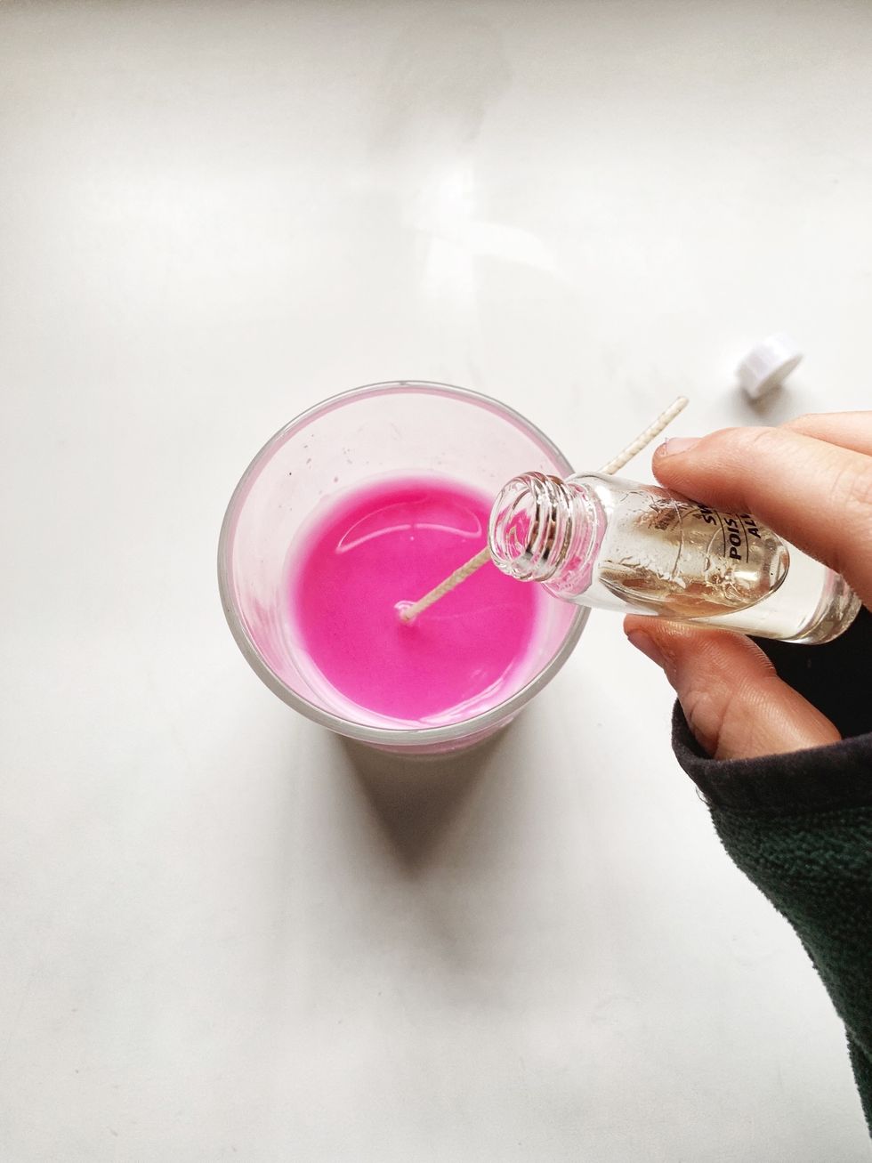 After wax is melted, pour the melted wax into the candle jar, and hold the wick upright. Pour essential oil in. Let wax sit for 10 minutes.