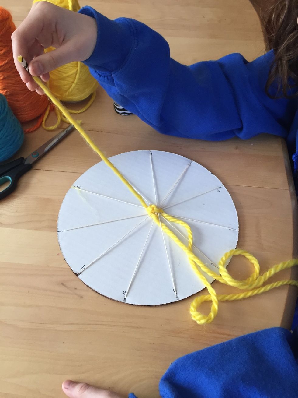 After you go under and over four or five strings, pull the excess yarn through.