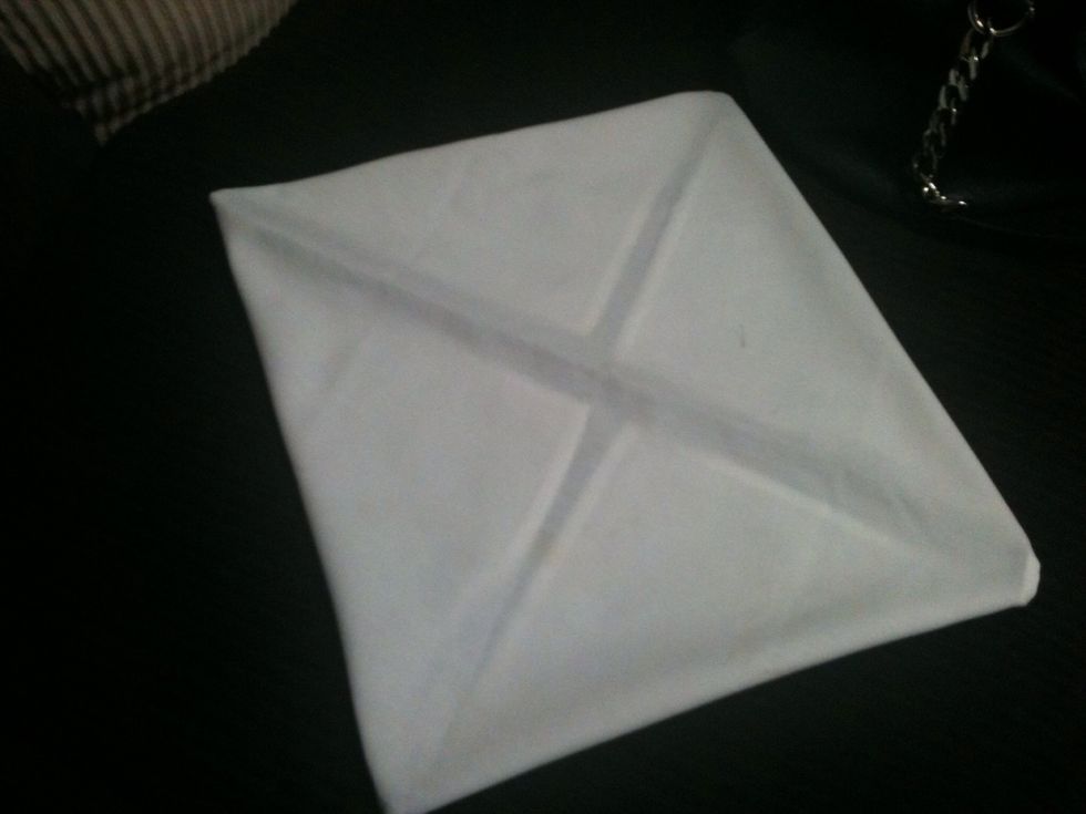 After you have folded all four sides, carefully flip the napkin over. So, pretty much all the folded corners you did previously are facing the counter.
