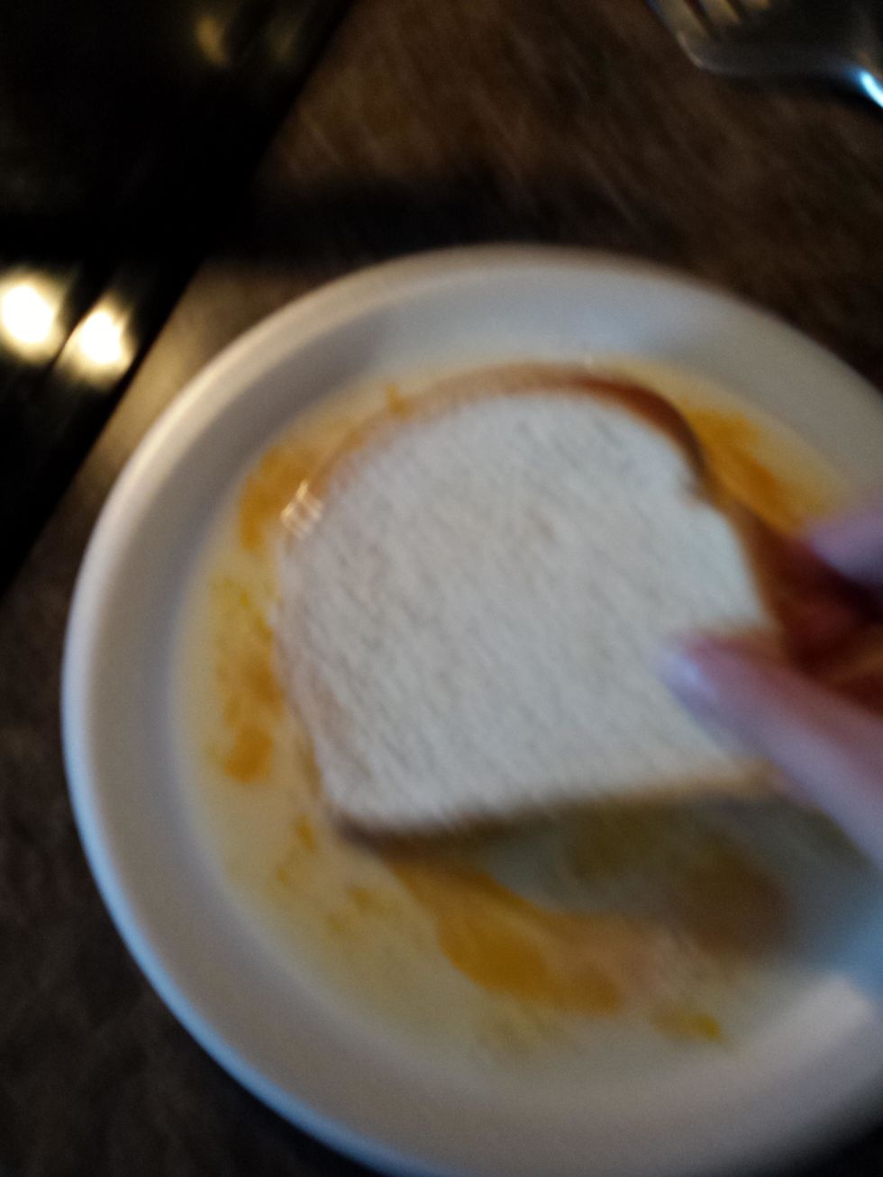 After you put the egg and milk on the plate and stir it you dip the bread in the milk and egg and dip the bread on the other side.