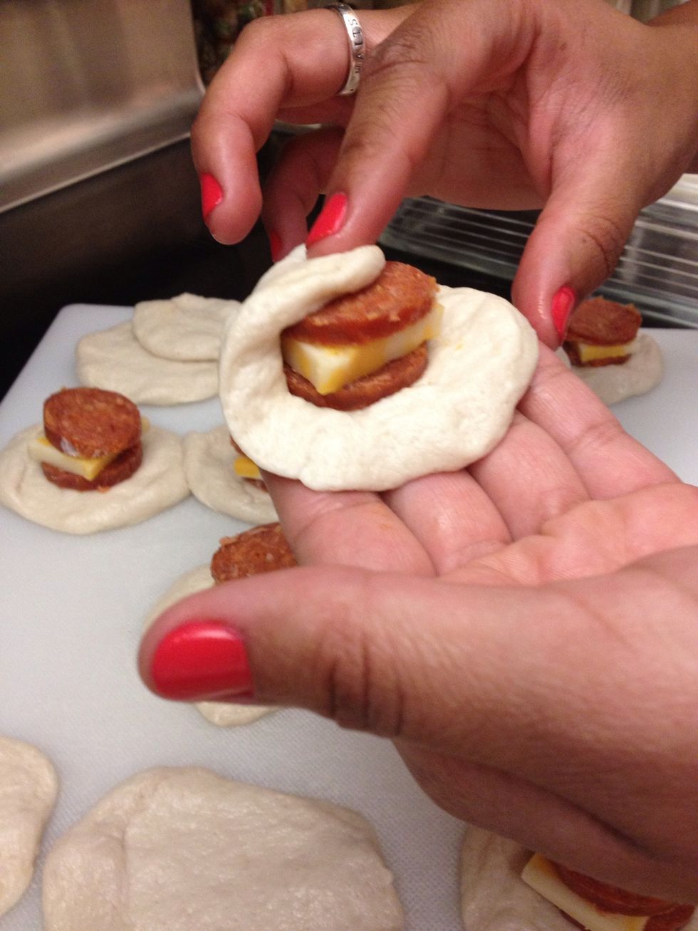 After, you start rolling and stretching the dough over the pepperoni and cheese until it is completely covered.