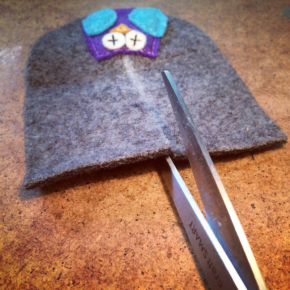 After you've stitched the owl to the front of the bootie then tie up the ends. Next you cut along the chalk line. This is the opening of the bootie you're creating.