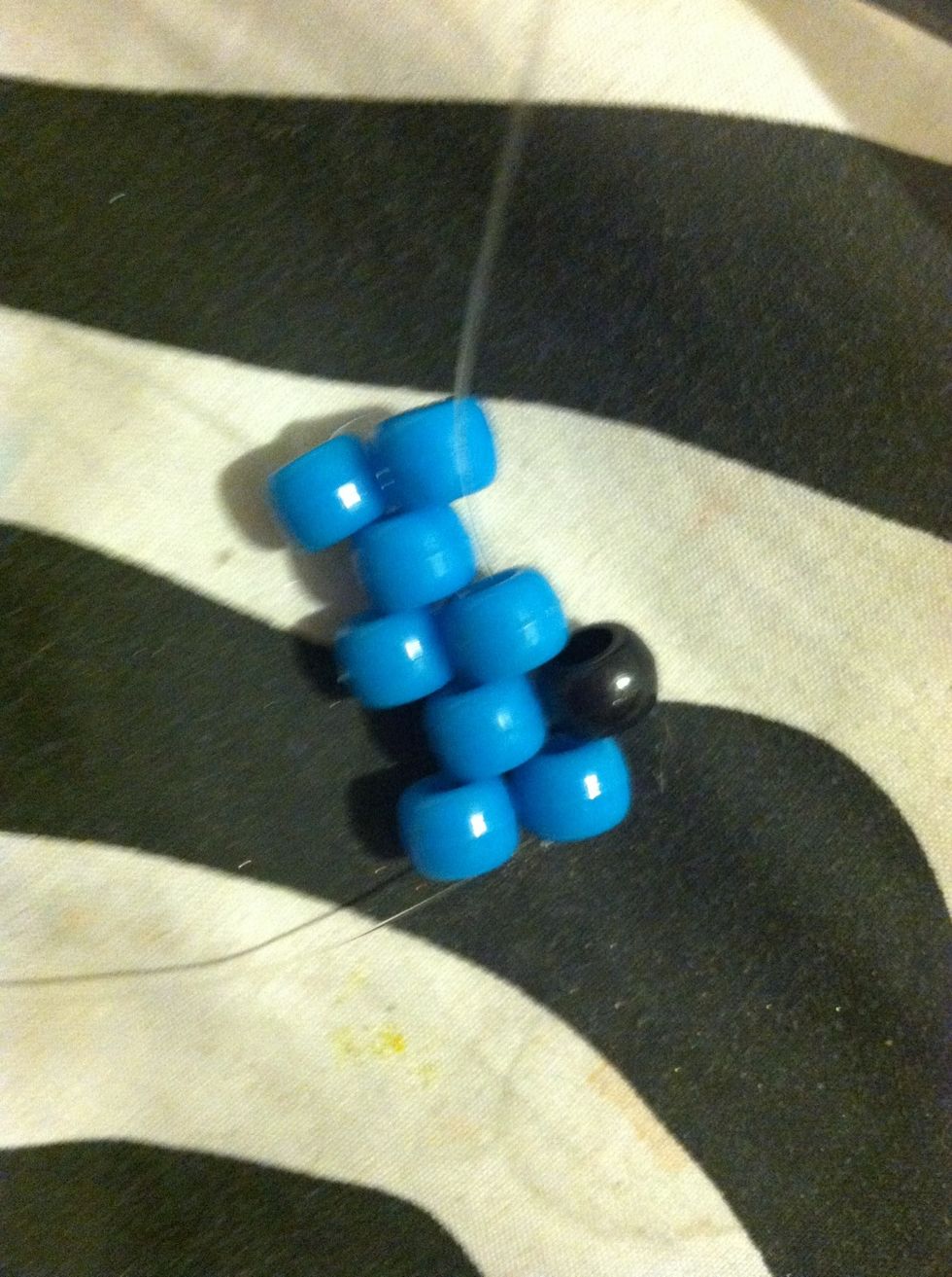 After You've Strung Through the First Bead , add A Black Bead And String It Through The Next blue Bead