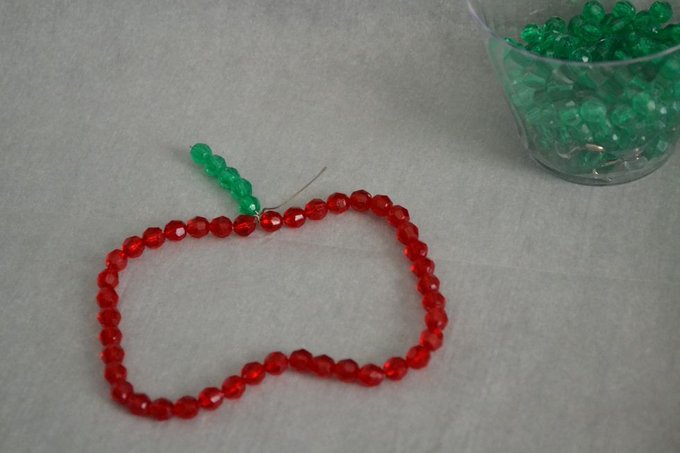 After you've  twisted the exposed wire to connect both sides bend and shape your wire. Then add a couple of green or brown beads to one half of the stem and leave another piece without beads.