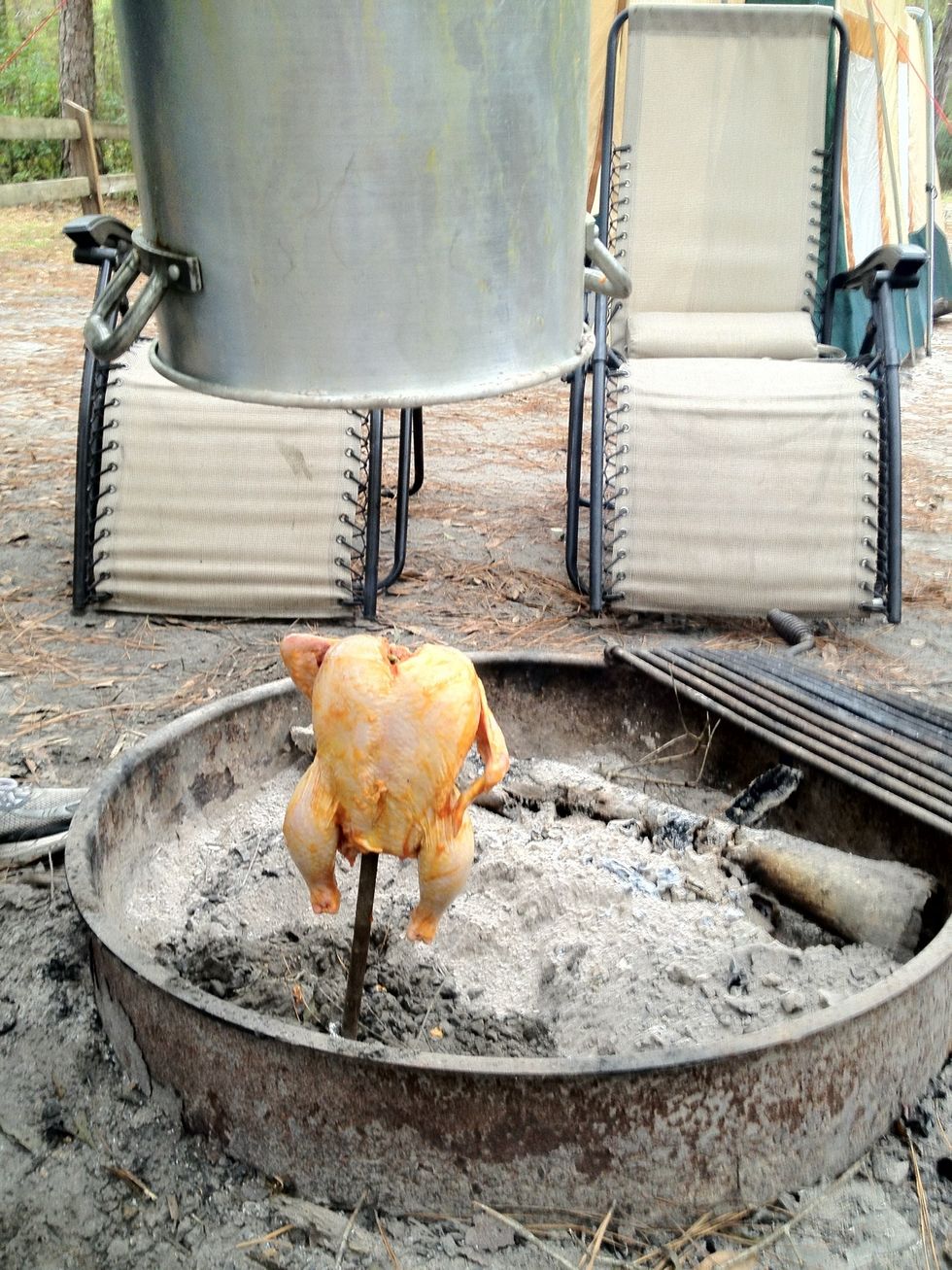After your fire has burnt down to just coals, put your chicken on a stick with aluminum foil on the bottom, clear out the coals ( so your stick doesnt burn) and stick it in the ground