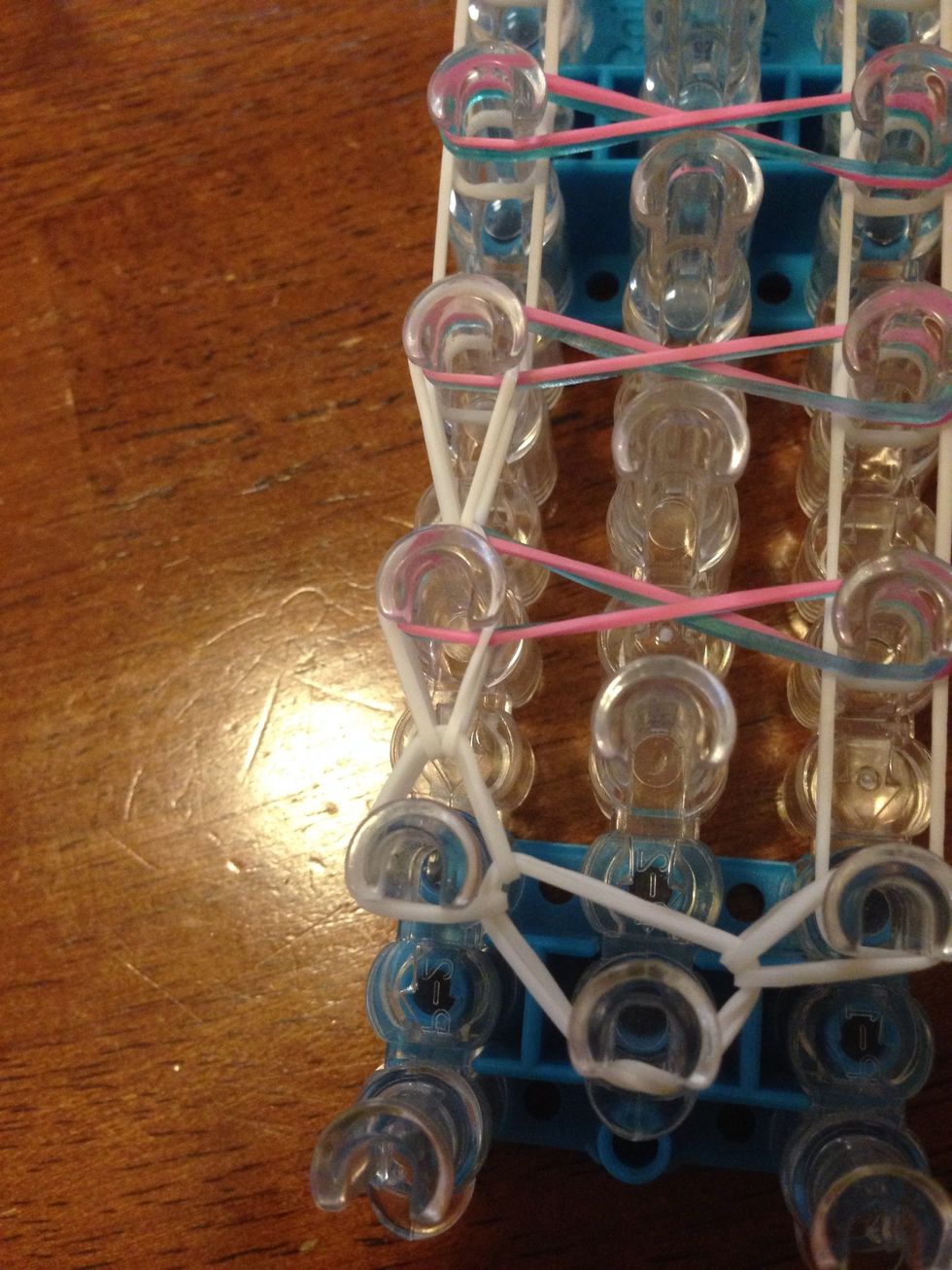 Again, go inside the pin and grab the loose band, stretching it over to the next pin up.