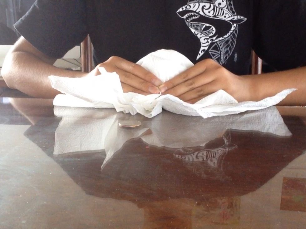 Again slide your napkins back revealing the coin is still there. But, this time drop the ball in to your lap and place the empty paper towels back.