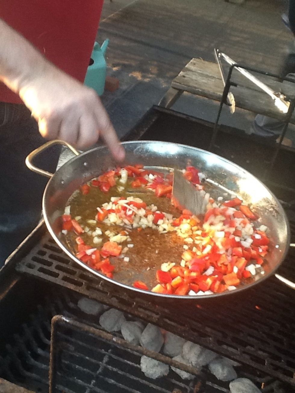 Ahora a\u00f1ade m\u00e1s aceite de oliva, las cebollas y los pimientos y coc\u00ednalos bien.