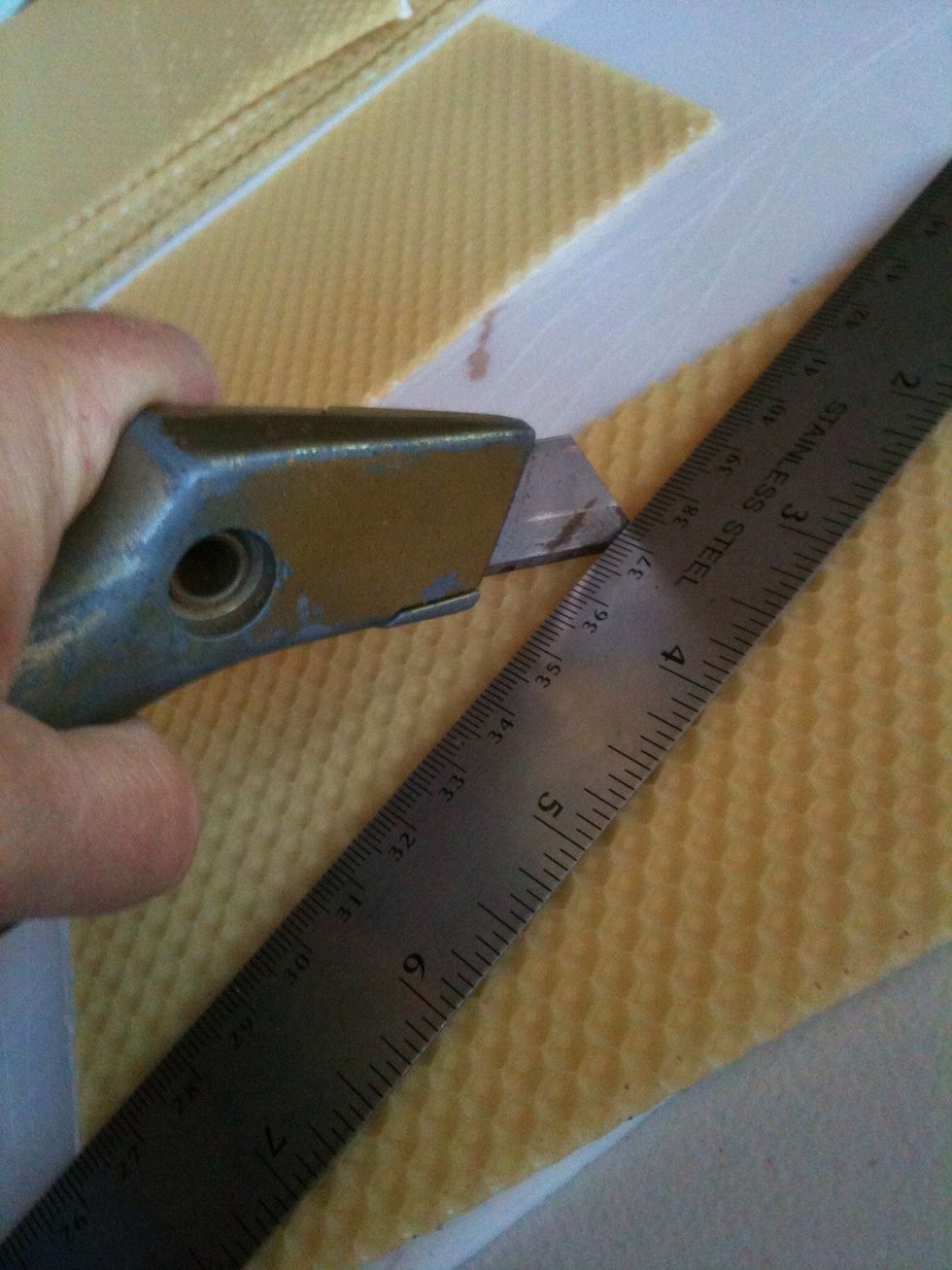 Align the top of the ruler between the two slits and cut along the top edge of the ruler to remove a triangle shaped piece of wax.