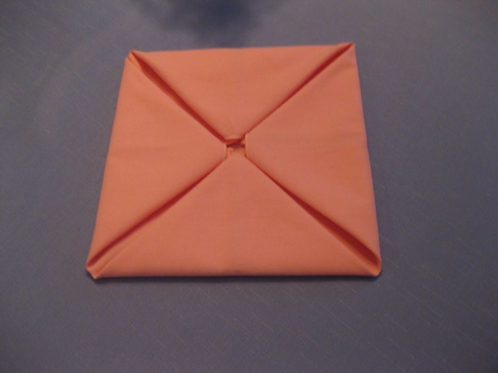 All four corners should again be folded to the center of the napkin.