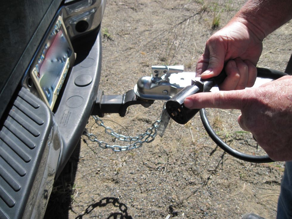 Almost done! Now plug in the power cord that goes to the trailer. Your tow vehicle has a plug back there by the hitch. There's a slot that needs to be correctly lined up, see where I am pointing.