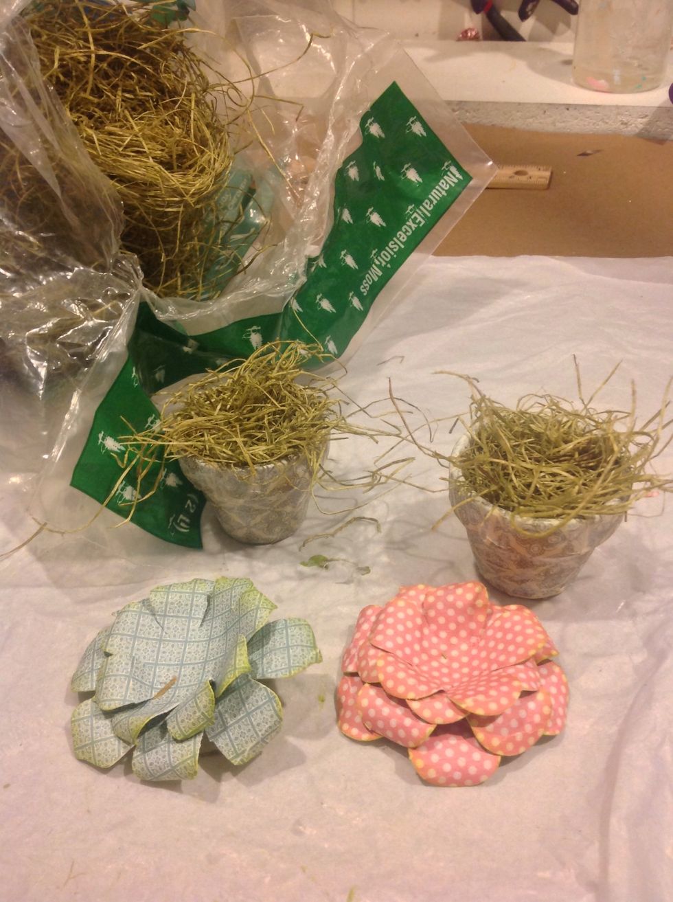Almost there! Add Spanish moss inside your pots. Make sure there is excess to adhere both the votive to and to have a bit poking out under the flowers.