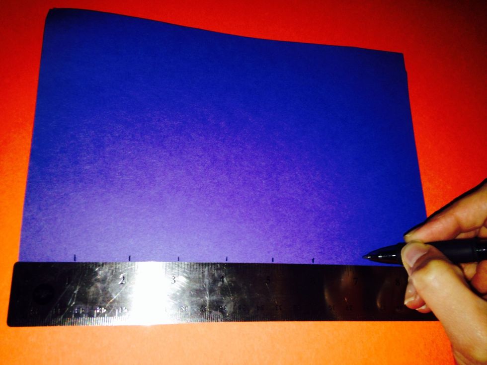 Along the folded side of the paper, measure and mark every inch.