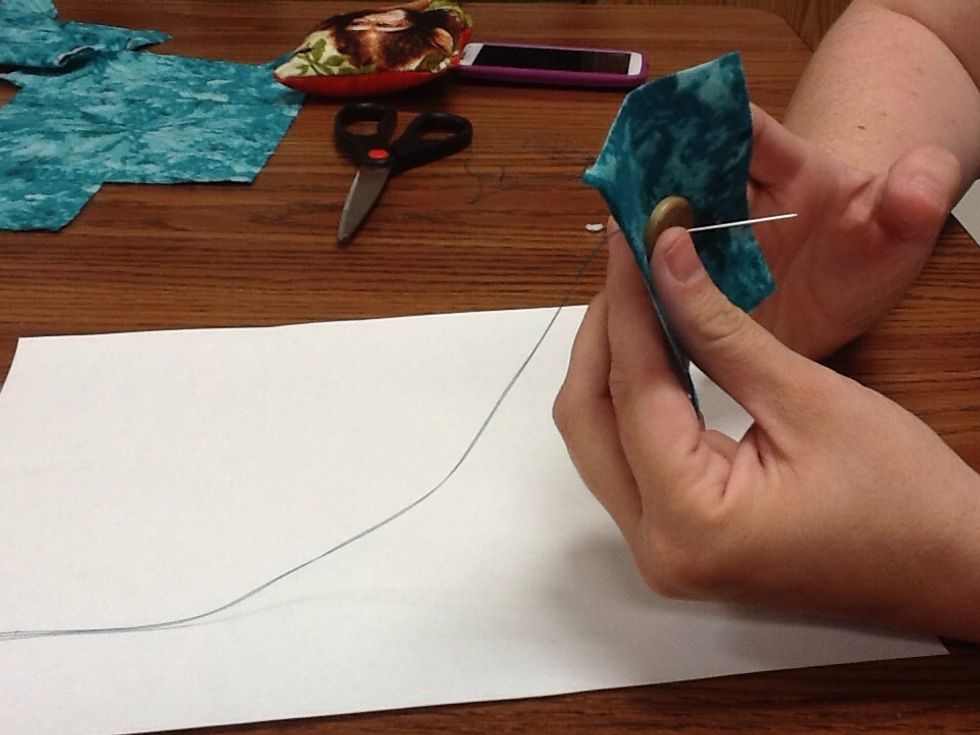 Always start from the back of the button- put the needle through the fabric then through one hole of the button. Pull tight to the knot.