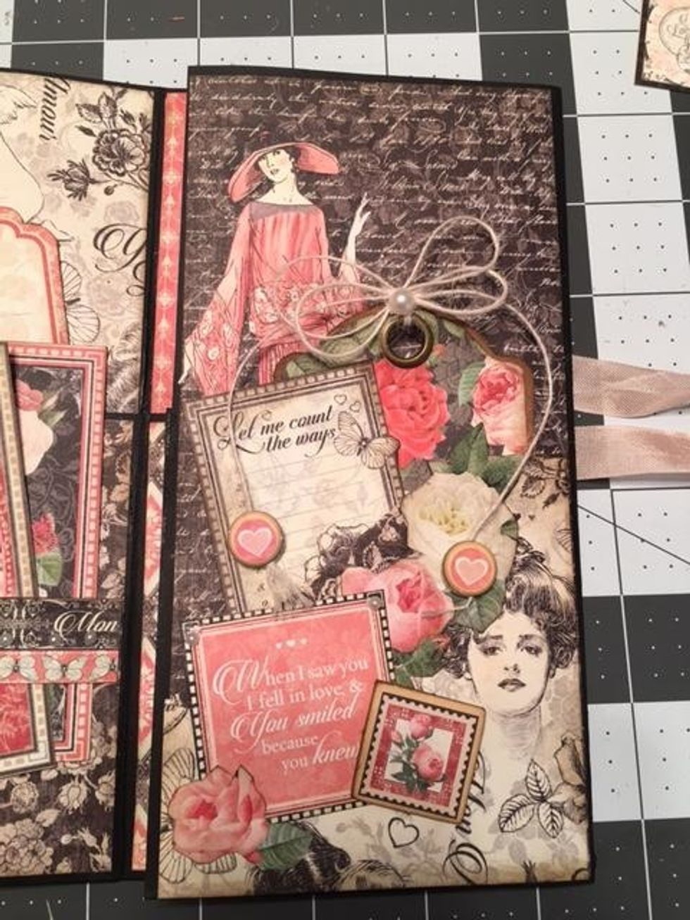 Angle pocket section:  Fussy cut out the lady from the 8x8 Mon Amour paper. Glue her to the inside section of the pocket.  Cut out roses & a sentiment to glue to the pocket. Add a chipboard rose stamp