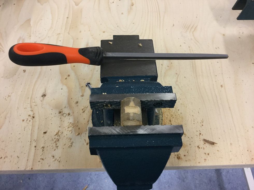 Anv\u00e4nd en fil och slipa en sk\u00e5ra p\u00e5 den korta rundstaven. Sk\u00e5ran ska vara p\u00e5 motsatt sida h\u00e5let. Gummibandet ska passa i sk\u00e5ran.