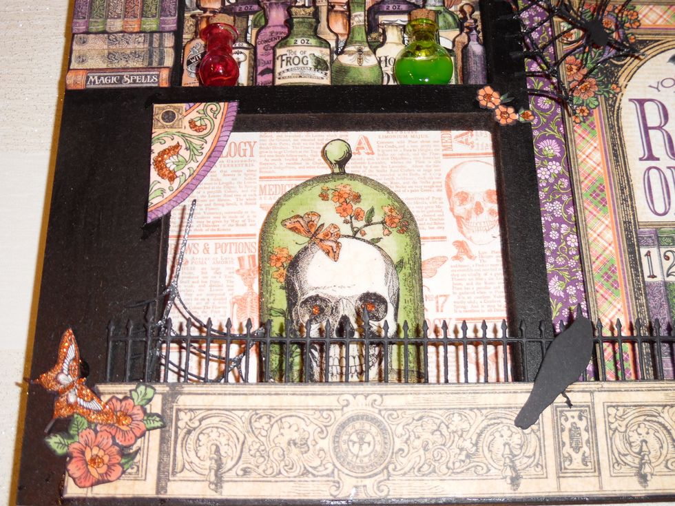 Apothecary jar and bottles were cut from Rare Oddities paper and coated in Glossy Accents to give a glass like finish. Iron railing was cut from black card using a Memory Box die and a die cutter.