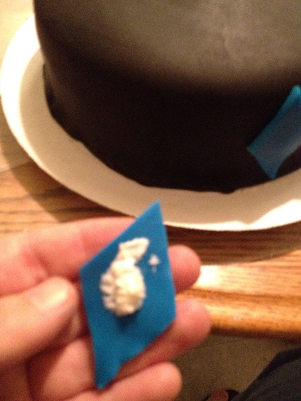 Apply a small amount of frosting to the back of the diamonds and stick them around the cake.