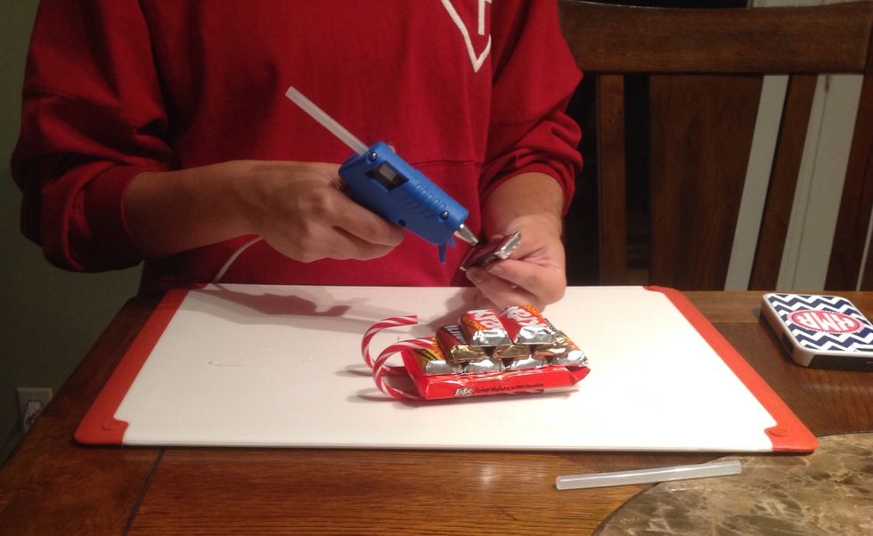 Apply drops of hot glue to the bottom of the two Krackel bars and place them on top and in between the Hershey bars.