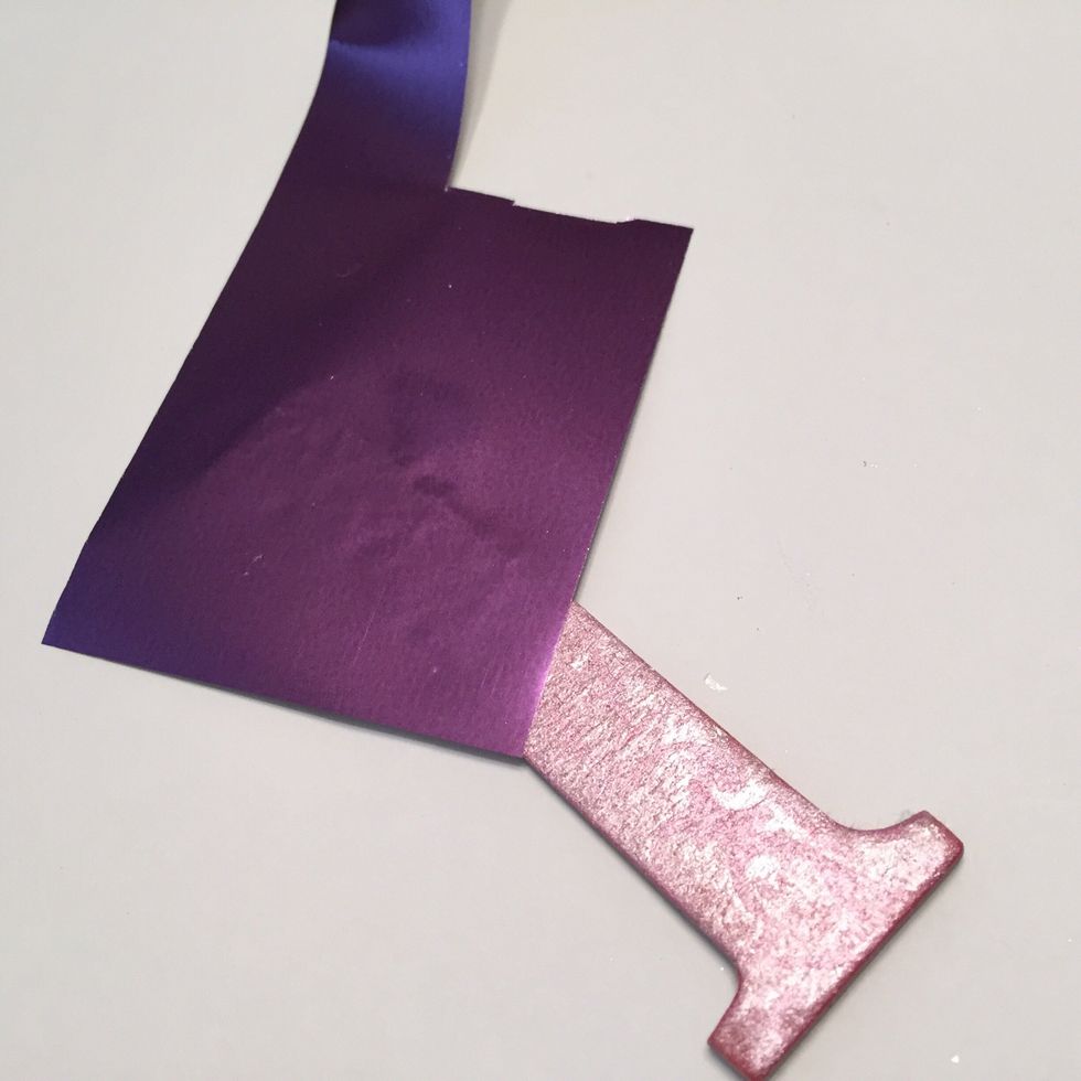 apply Plum Crazy Designer Foil over letters and burnish on with your finger or a bone folder. move sheet around letter until the designs have been completely foiled.
