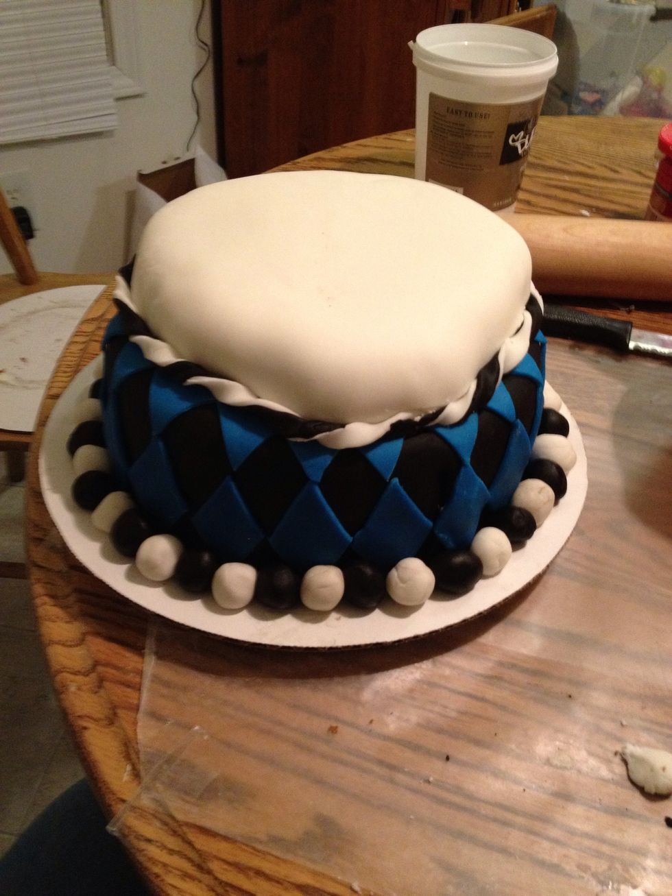 Apply the twisted fondant string around the base of the Skullette layer. Roll up balls of the black and white fondant and place them around the base of the cake.