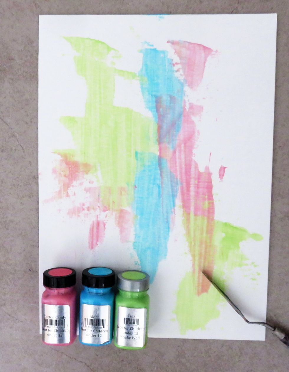 Apply three bright colors of Art Anthology paints over the flat canvas using the artist knife only. Make it with a very thin layer of the paint and let it dry (will be fast drying time).
