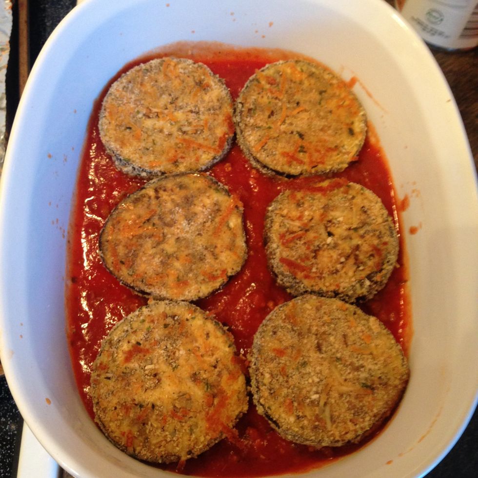 Arrange a single layer of the baked eggplant slices on top of the sauce.