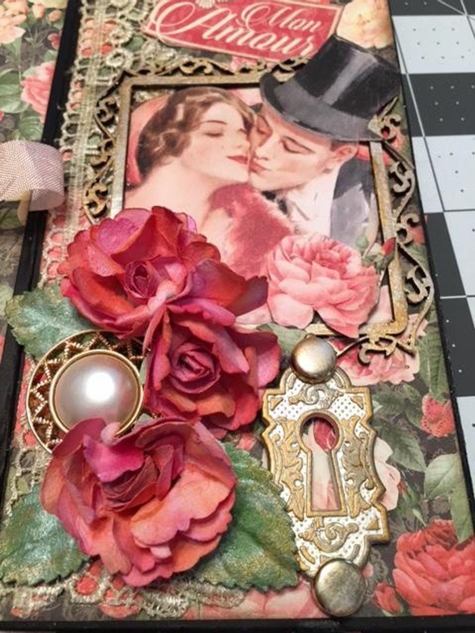Arrange and glue down fussy cut paper roses, Prima roses & leaves,a pretty button,& Graphic 45 key hole.  Cut out the "Mon Amour" from the Mon Amour 8x8 paper and glue it above the frame.