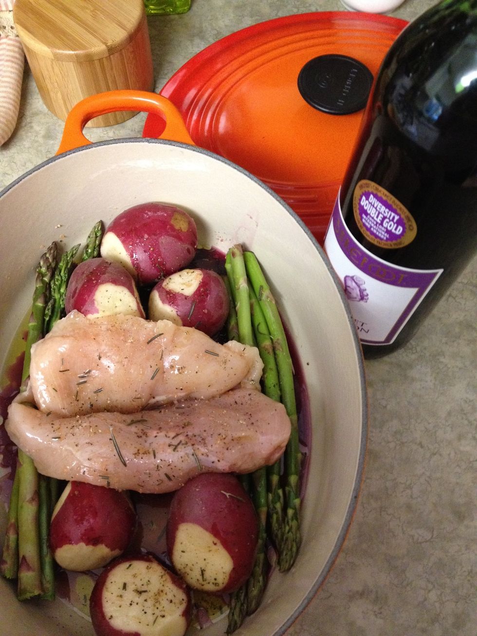 arrange the chicken, potatoes, and asparagus in the Dutch Oven. Drizzle with olive oil & spices, and fill a half inch with chicken broth (we forgot broth at the store, so we used red wine and water.)