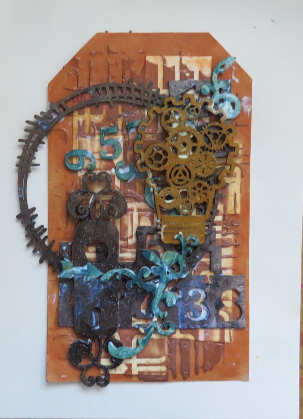 Arrange the chipboards over the tag as shown and glue them with gel medium.