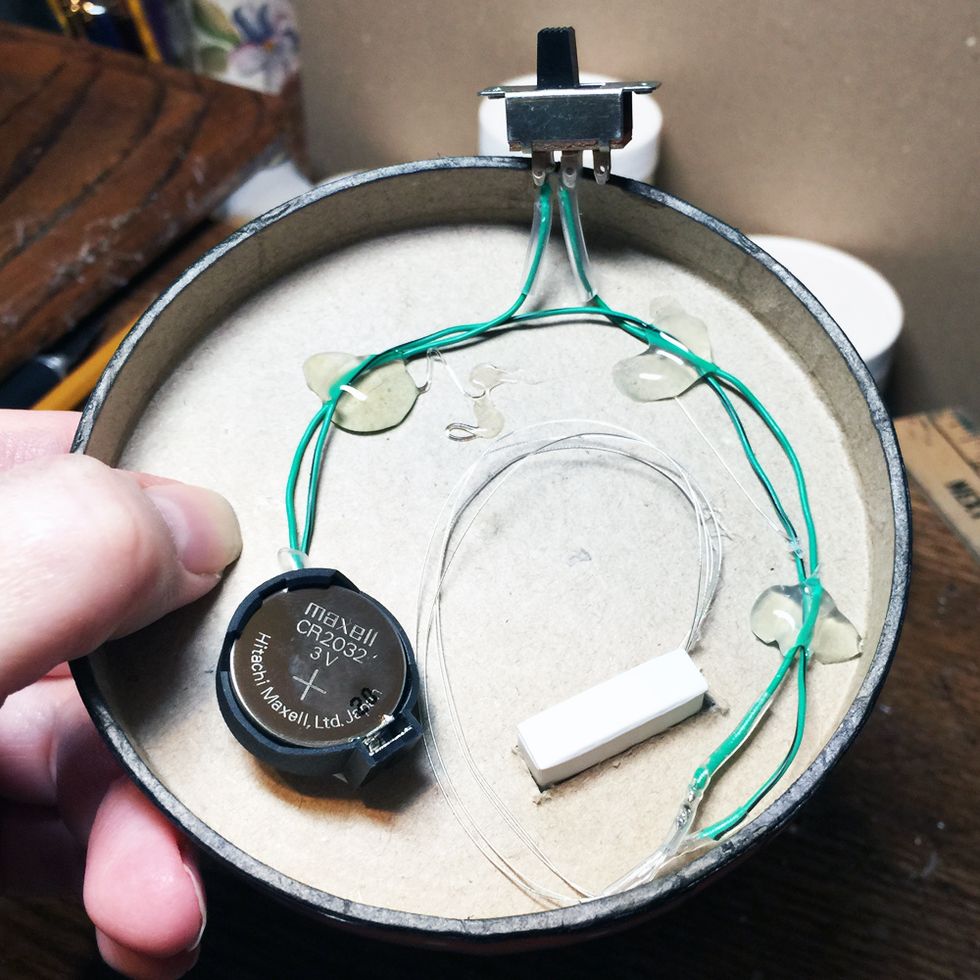 Arrange the LED wires and parts so that the lid can still go on the box and hot glue them down. (You can see the small bit of matchbox sticking through the hole in this photo.)
