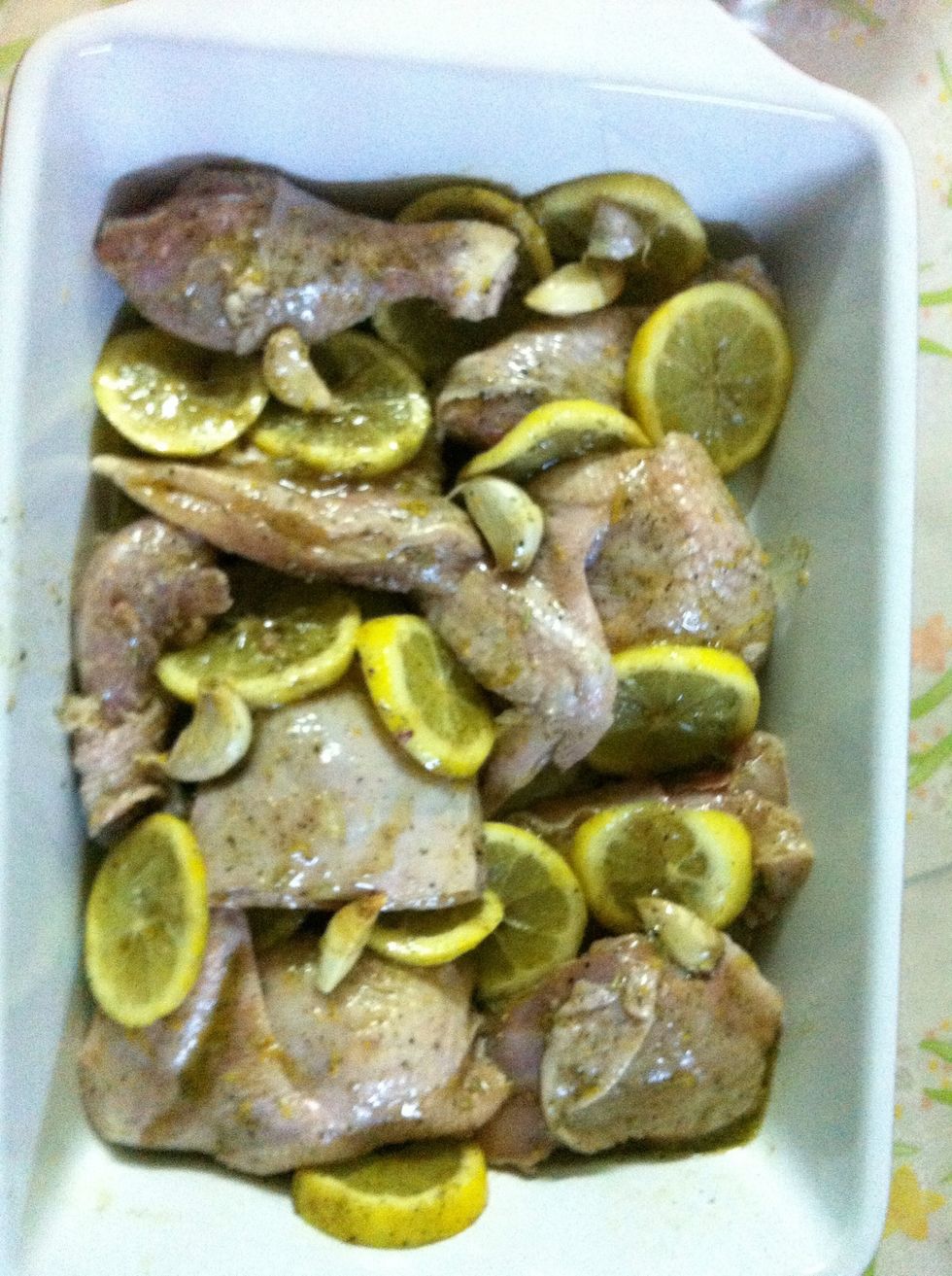 Arrange the peices of chicken in a baking dish. Try to over lap the lemon slices between the chicken peices. Add the garlic cloves on top so that they don't burn. Drizzle with remaining marinade.