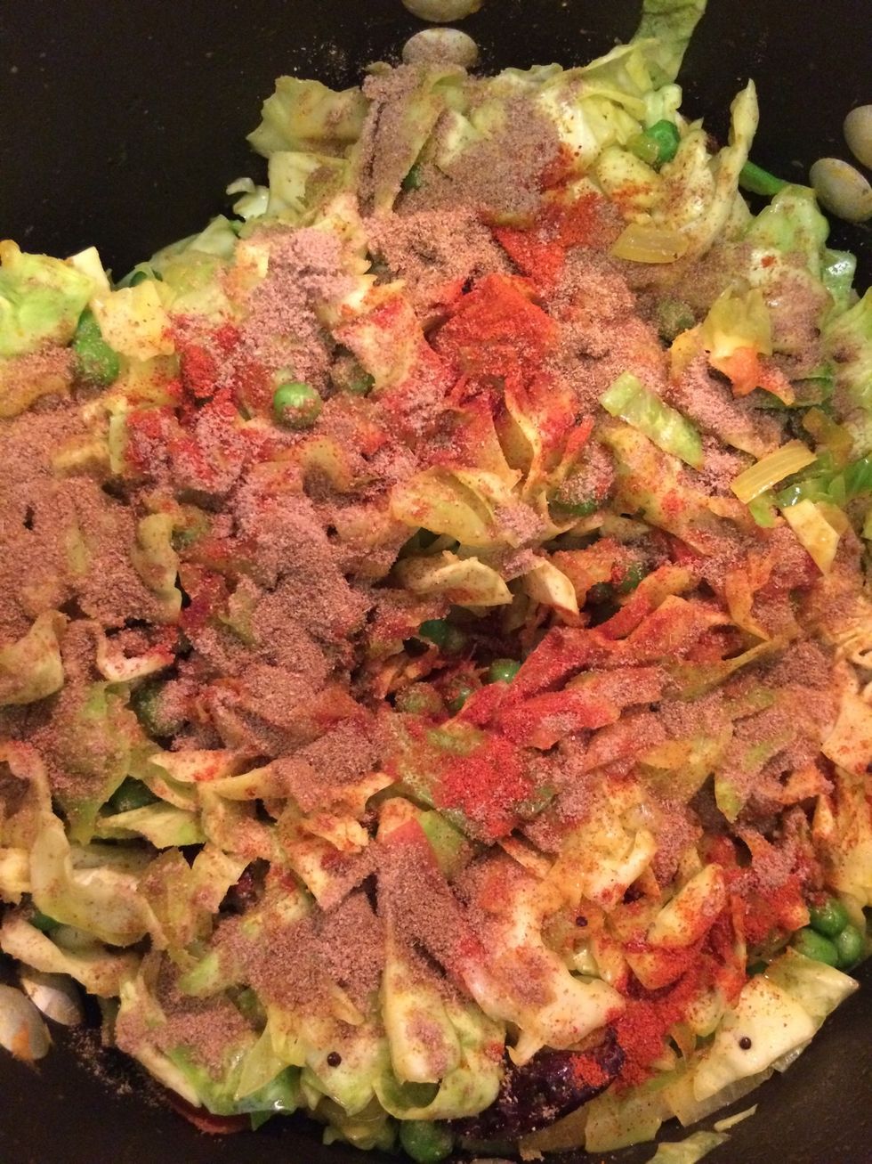 As the cabbage starts to water and shrink, add cayenne pepper, ground cumin as well as ground coriander. Keep mixing to prevent the cabbage from blackening.