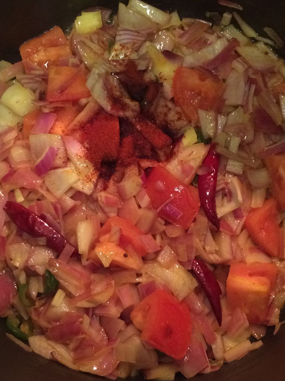 As the mustard seeds pop, add the red onion, tomato and 1/2 teaspoon of paprika. Mix well and let the onion become translucent, almost to the point of caramelizing.