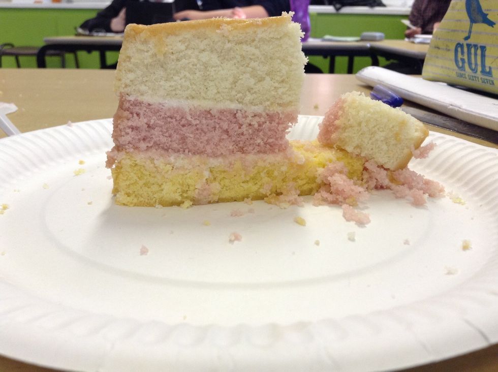 As the pink layer is eroded, it can no longer support the top layer, therefore it falls. It gradually is bashed around and eroded into small pieces of rock which helps erode the cliff further.