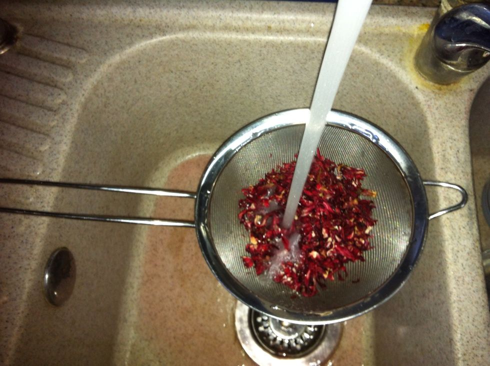 As the water is coming to a boil, rinse the hibiscus. Place a cup full over a large strainer and rinse under cold running water to clean it from dirt or dust.