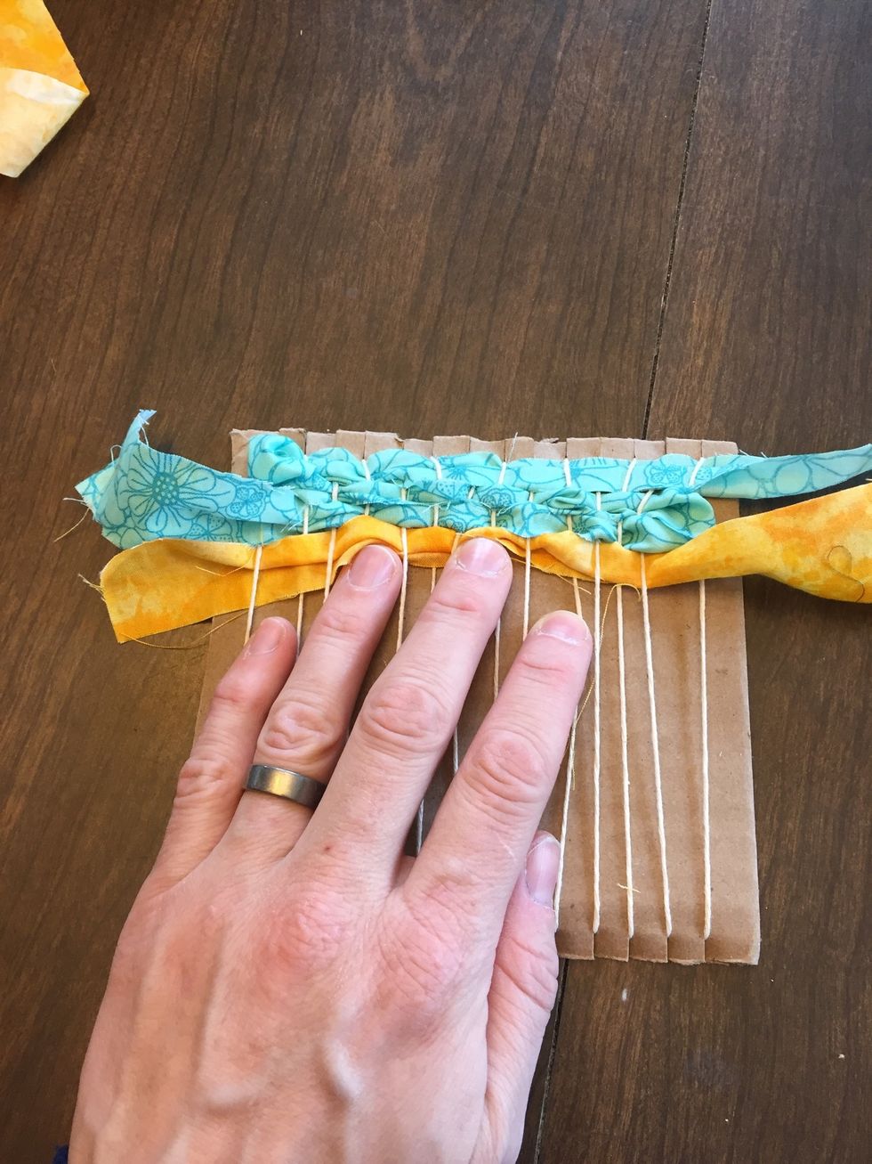 As you continue to weave, use your fingers to push the fabric up against the top of the loom, creating a "bunched" and tighter weaving.