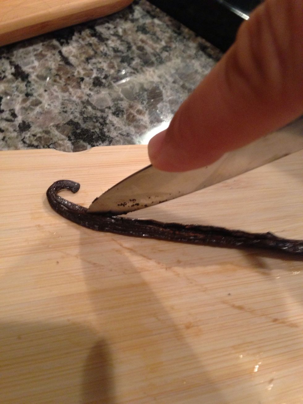 At this time, go ahead and split your vanilla bean. Lay the bean flat and while pressing the top of the bean to keep it in place, run the tip of your knife down the length of the pod.