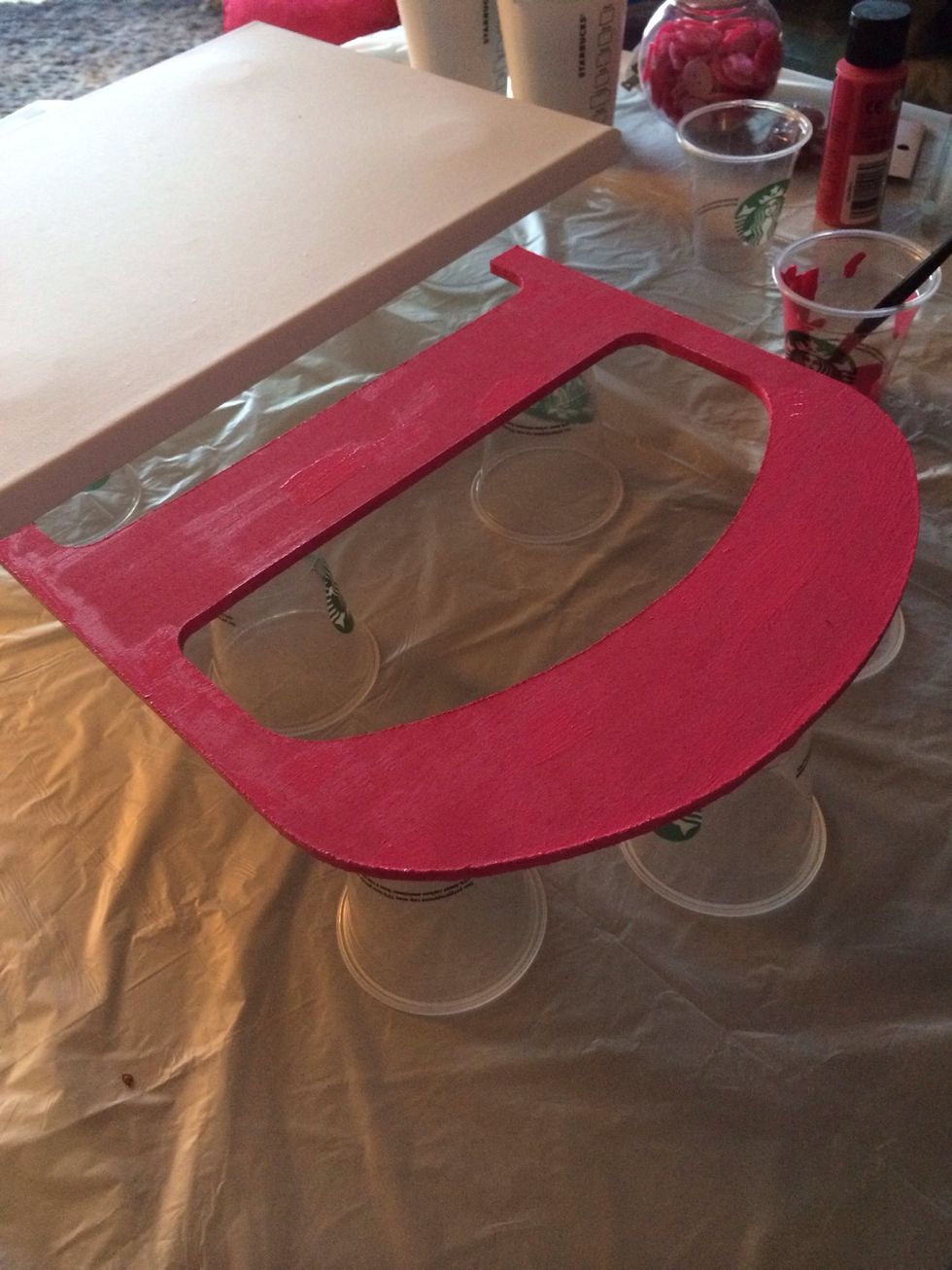 Atop some small cups (bathroom cups work great), paint your wooden letter a color that corresponds to your button selection. Be sure to get the edges! Visually, this is important after buttons go on.