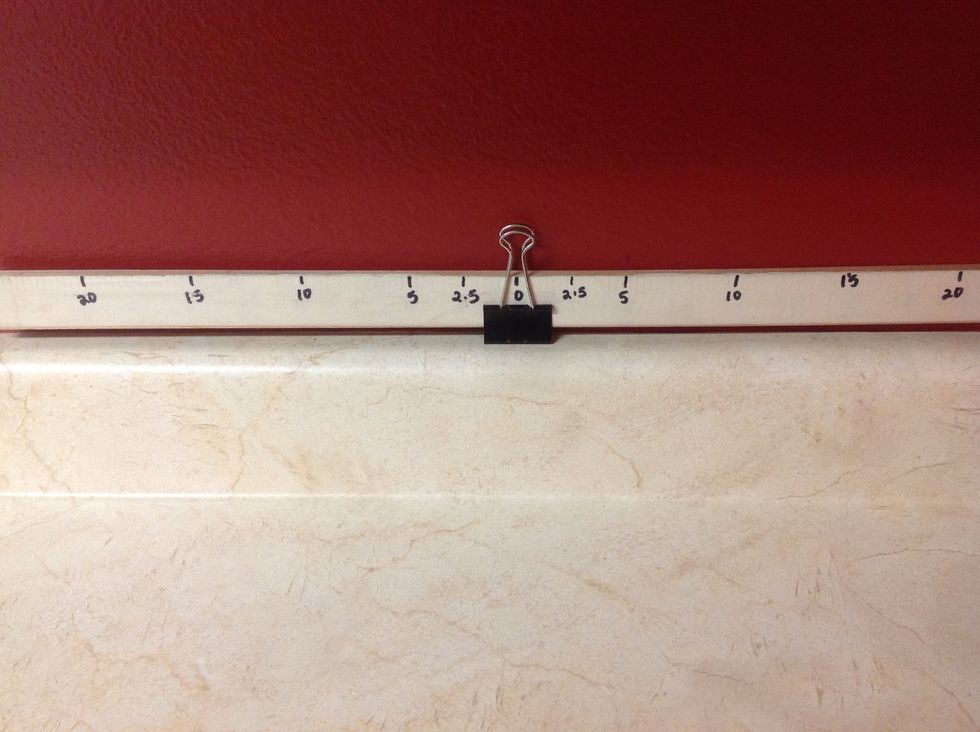 Attach a binder clip under the zero position (middle) of the half-meter stick and flip both metal loops up.