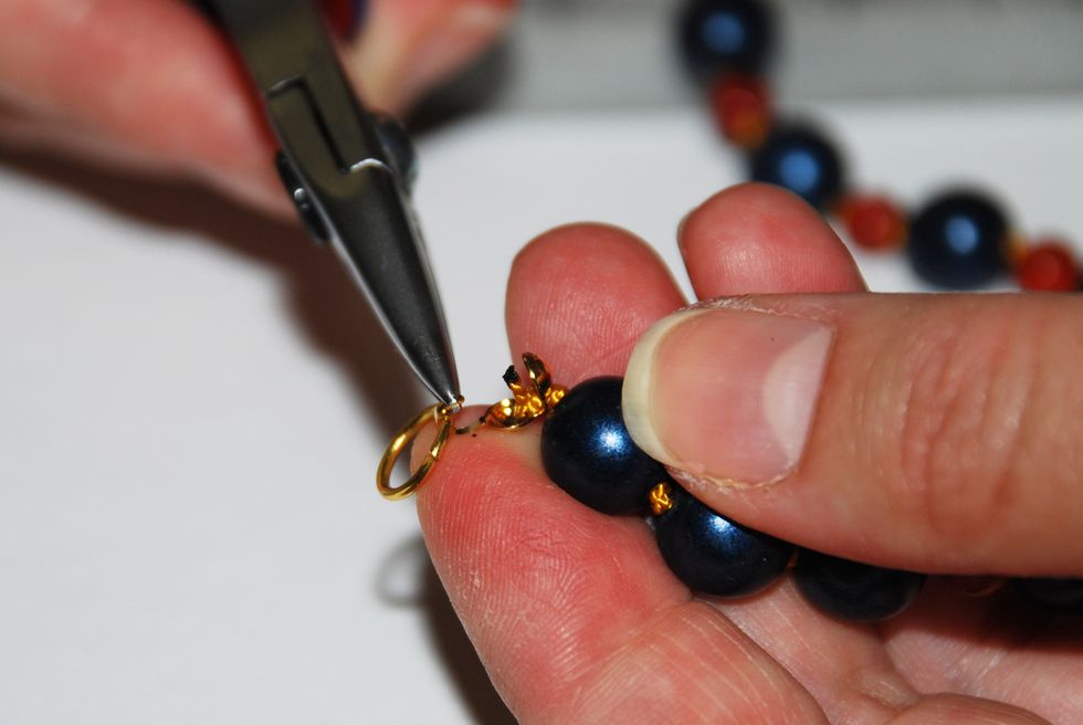 Attach a jump ring to the open hook of the clamshell end-cap, and using the tip of your chain nose pliers, curl the end of the hook so it encloses the jump ring.